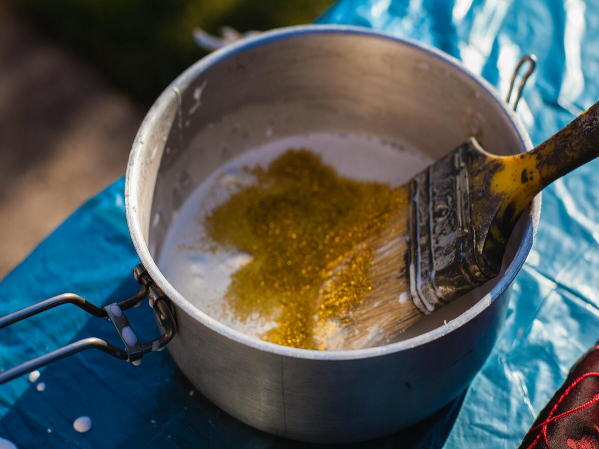 A person making a sauce in an aluminium sauce pan.