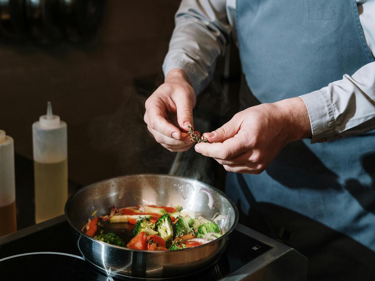 A man making a vegetable dish in an aluminium pot.