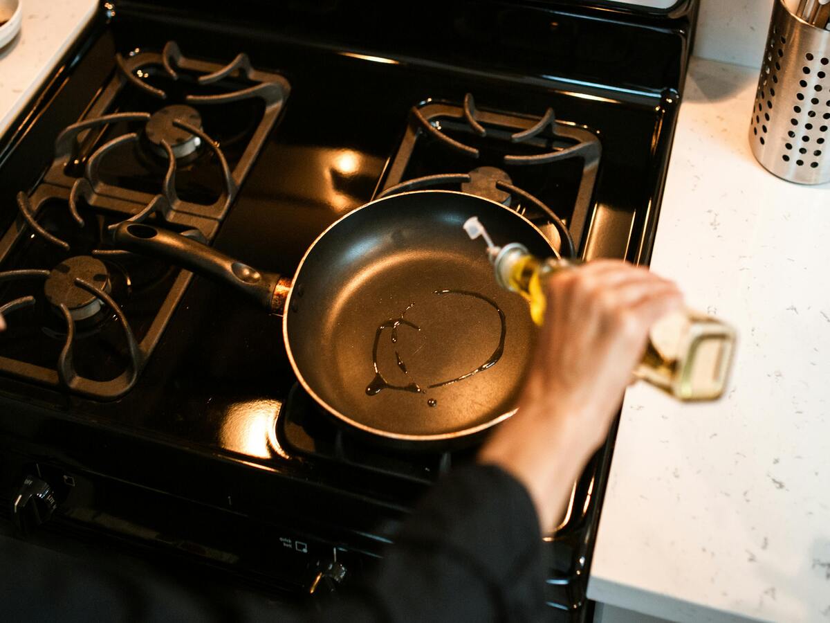 A person seasoning a cast iron pan with oil.